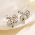 Elegant silver hollow bow earrings for women on a white ceramic tray with soft shadows - Silver