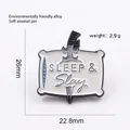 Gedetailleerd overzicht van de Sleep & Slay emaille speld van 26 mm bij 22,8 mm - Zwaard Door Kussen-Sleep & Slay