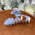Acetate hair claw with blue marble texture and gold lettering on a wooden tray - Blue Coffee Marble - 8 Teeth