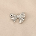 Detailed top view of a silver bow pendant with clear zircons on beige fabric - Teardrop Zirconia Bow (PJ0160) / Silver