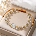 Close-up of a clear crystal evil eye beaded bracelet with gold accents on a gift box - White