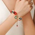 Detail van kerstarmband met rood-groene hars schakels en sneeuwvlok hanger op de pols - D1053 (Groene Sneeuwvlok)