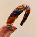 Detail of colorful knitted headband featuring handmade woven texture and black label - Orange Colorful