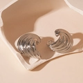 Macro-opname van zilveren C-vormige metalen oorbellen met getextureerd golfpatroon - Zilveren oorknopje - Zilver gestreepte geometrische oorknopjes