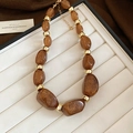 Detail of irregular brown acrylic beads with gold glitter and metallic spacers on white tray - Dark Coffee