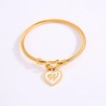 Golden stainless steel cable bracelet featuring a white heart charm with the letter W - Letter W