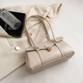 Sac à bandoulière beige vintage avec fermoir doré sur fond de veste de costume blanche - Blanc