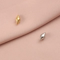 Nautische Seeschnecken-Anhänger in Gold und Silber auf weichem rosa Stoffhintergrund - Scharfe Schnecke / Stahlfarbe