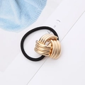 Detail of black elastic hair tie with golden metal knot on a clean white background - Gold Nine-Ring Knot