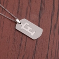Gros plan d'un pendentif lettre en acier inoxydable argenté sur fond en cuir sombre - Lettre F