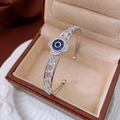 Macro shot of silver zircon floral open bangle with evil eye design in a jewelry box - Silver