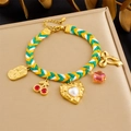 Detail of colorful woven bracelet with cherry, pearl heart, and bow charms on golden base - Cherry and Pearl Heart Style (B1800)