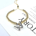 Detail of adjustable gold beaded bracelet with silver balloon letter W charm on card - Letter W