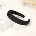Close-up of black satin padded headband with handmade label and soft texture - Black