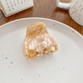 Elegant amber marble acetate hair claw clip for ponytail on a white ceramic plate - Gemstone Coffee