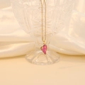 Golden cross chain necklace with a translucent pink heart crystal pendant on silk fabric - Rose Red