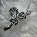 Bow-shaped hair claw clip in a metallic silver finish on a textured white background - Bowknot Claw Silver 13cm