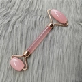 Rouleau facial en quartz rose à double extrémité avec manche doré sur fond de fourrure grise - Rouleau Rose