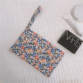 Floral cotton pouch with zipper and handle strap shown in a flat lay detail view - Red Blue Floral