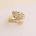 Macro shot of gold snake-shaped ring featuring sparkling white and green zircon stones - Adjustable Open / White