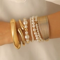 Detailed view of layered gold bangles and white pearl bracelets on a woman's wrist - Layered Bracelet Set (30) / 4-Piece Set (Inc. Gold & Pearl) / Gold/Pearl White