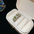 Nahaufnahme eines Vintage-Rings mit olivgrünen Edelsteinen und Diamanten in einer Box - Olivgrüner Ovaler Reihenring-Stil (Silber)