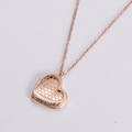 Dettaglio del ciondolo a cuore oro rosa con motivo a nido d'ape e incisione forever - Oro rosa