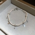 Detalle de pulsera de doble capa con perlas y dijes de estrella en terciopelo - Plateado