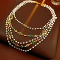 Dettaglio macro di una collana di perle multistrato con gemme colorate e chiusura dorata - Collana Oro Colorato