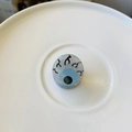 Detailed view of a round eye charm with silver glitter finish and blue iris detail - Mini Eyeball