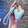 Light blue heart leather keychain with woven strap and black ring on grey texture background - Letter V