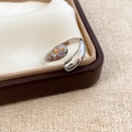Macro view of crossover open ring with colorful zircon droplets on a leather box - Silver