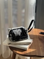 Detail van zwarte canvas handtas met wit vlinderborduurwerk op een rustieke houten tafel - Vlinderborduurwerk