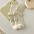 Off-white cotton crew socks with green hello text and minimalist ribbed knit texture - Cream