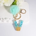Letter V resin keychain with blue turquoise stones, gold glitter and mint green pompom - Letter V