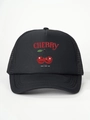 Detailed close-up of a black mesh trucker hat with cherry print and curved brim stitching - One Size / All Black