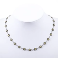 Close-up of daisy charms necklace with black petals and yellow center on a white bust - Steel + Black