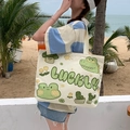 Cream canvas tote bag with green Lucky lettering and cute cartoon prints in beach setting - Lucky Frog