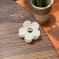 Close-up of a white flower hair claw clip with metal spring on dark wooden background - Jelly White
