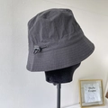 Close-up of charcoal grey nylon bucket hat featuring adjustable elastic drawcord toggle - Black