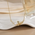 Detailed shot of a gold bird pendant with white pearl on a ceramic tray - FN0142 Bird on Branch With Pearl