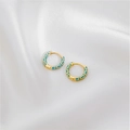 Detail view of gold hoop earrings with light blue geometric patterns on white silk fabric - Lake Blue