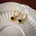 Detail van vintage hartenoorbellen in mat goudkleurig metaal met zwarte facet geslepen steen - Gouden Hart Ring