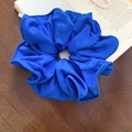 Détail de la texture d'un grand chouchou en tissu bleu Klein sur un livre avec perles - Bleu