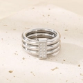 Detail shot of a silver triple-band ring with inlaid zircons on a beige stone surface - US 6 / Stackable Triple Layer (11mm) / Silver With Stone (KR36005-K)