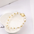 Bracciale di perle naturali con una medaglia di San Benedetto su un piatto bianco - Medaglia di San Benedetto