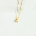Detailed close-up of a minimalist golden letter A pendant on a fine clavicle chain - Letter A