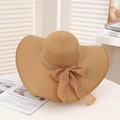 Detail of wide brim straw sun hat with elegant chiffon bow on a white surface - Khaki & Khaki
