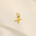 Detailed close-up of a gold stainless steel letter X pendant on soft silk fabric - Letter-X