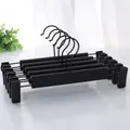 Macro detail of five matte black adjustable metal pants hangers with sliding clips - Matte Black